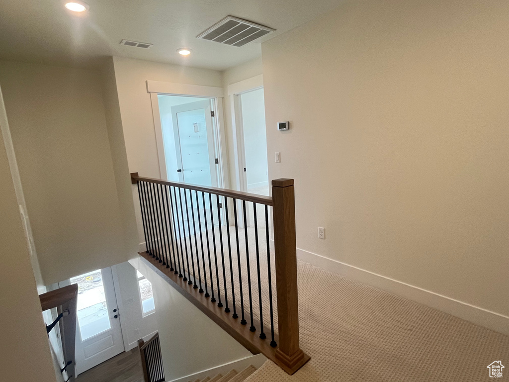 Hall with an upstairs landing, visible vents, and baseboards