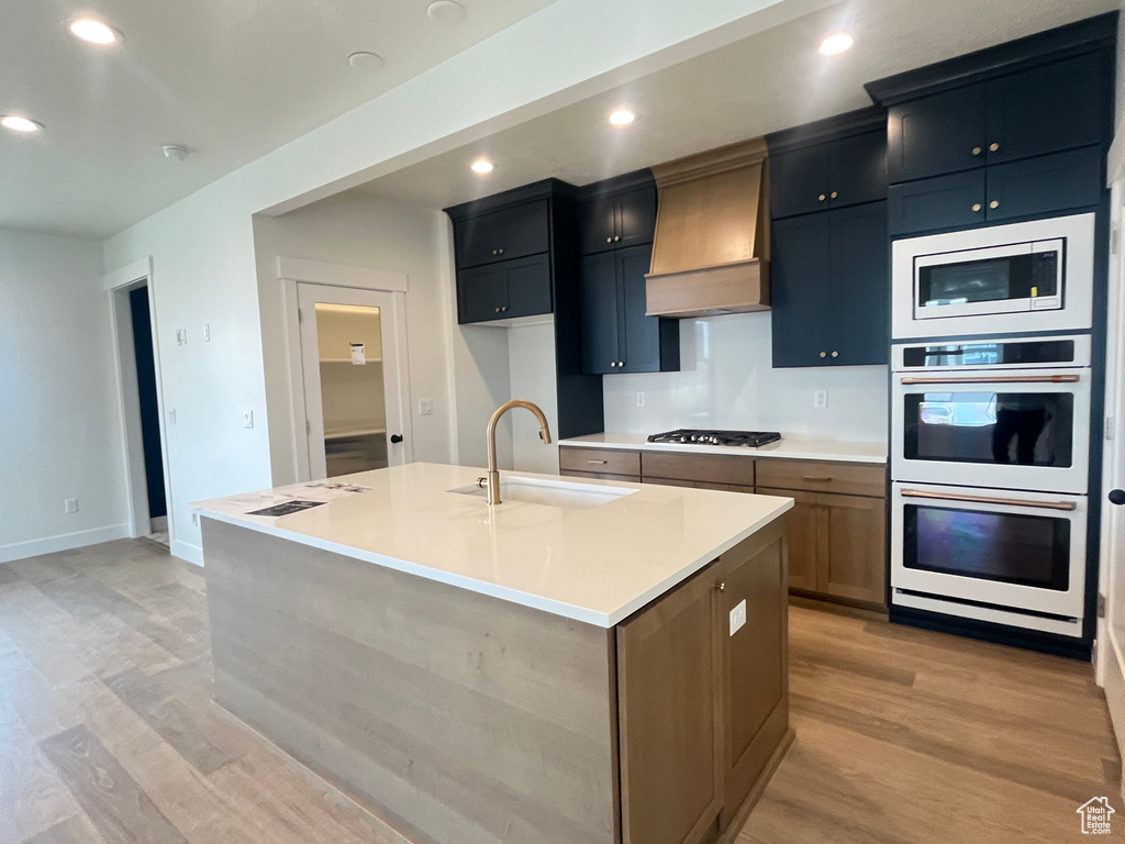 Kitchen with custom exhaust hood, a sink, double oven, gas cooktop, and built in microwave