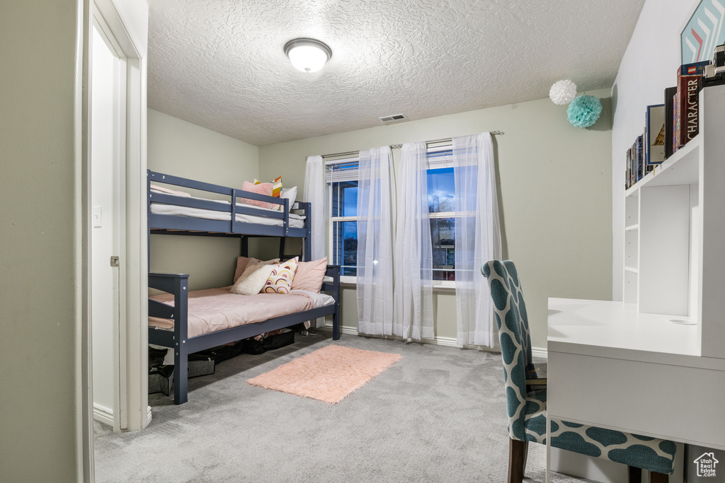 Bedroom with light colored carpet and a textured ceiling