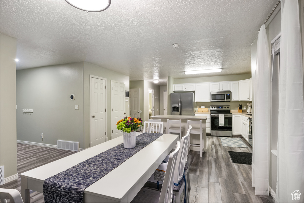 Dining space with a textured ceiling and dark hardwood / wood-style floors