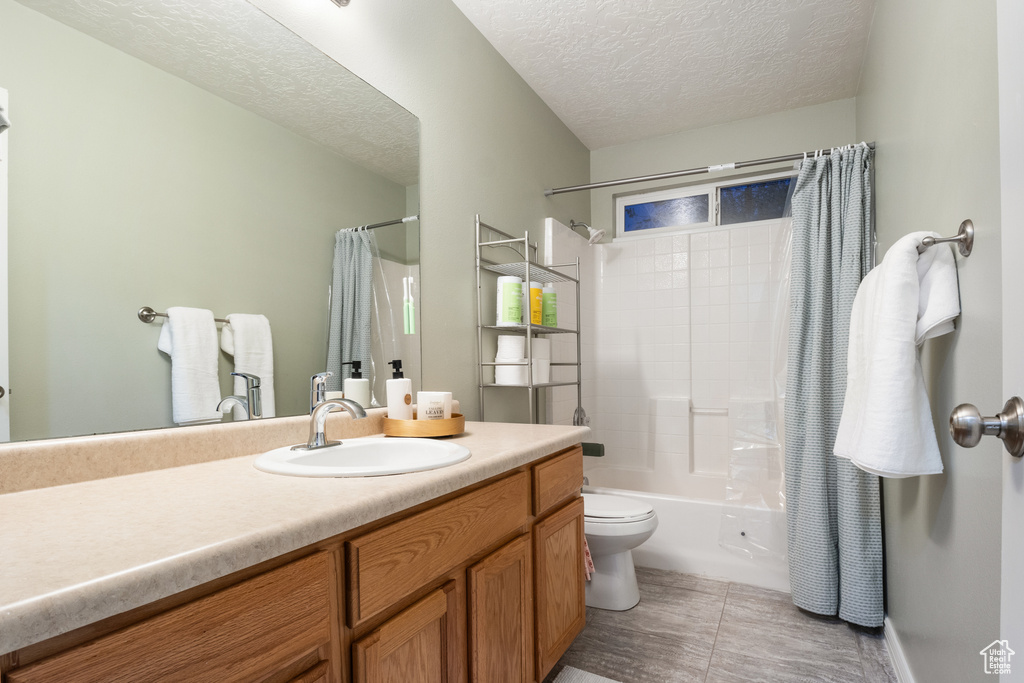 Full bathroom with shower / bathtub combination with curtain, tile patterned floors, a textured ceiling, toilet, and vanity
