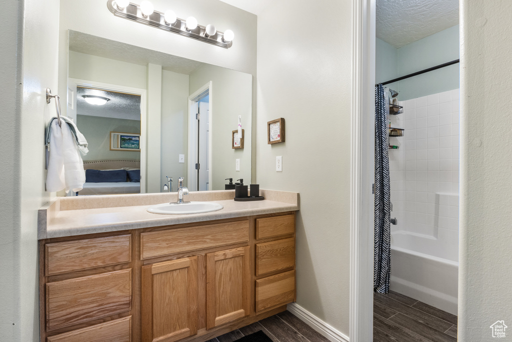 Bathroom featuring shower / bath combo with shower curtain, vanity, wood-type flooring, and a textured ceiling