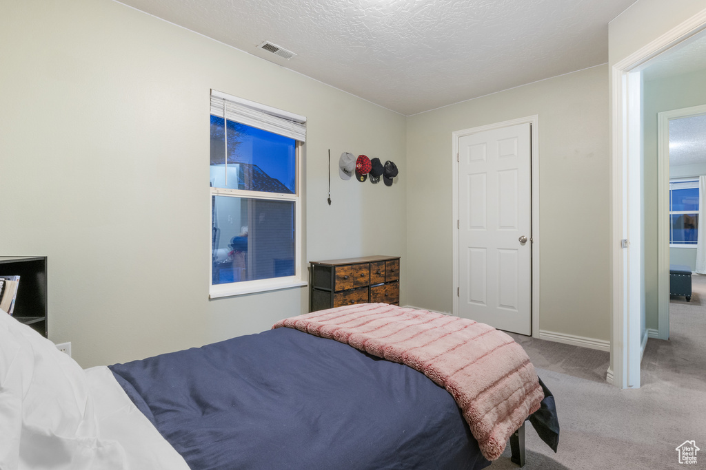 Bedroom featuring a textured ceiling and light colored carpet