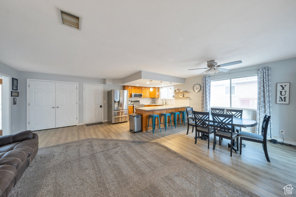 Dining area with light hardwood / wood-style floors, ceiling fan, and sink