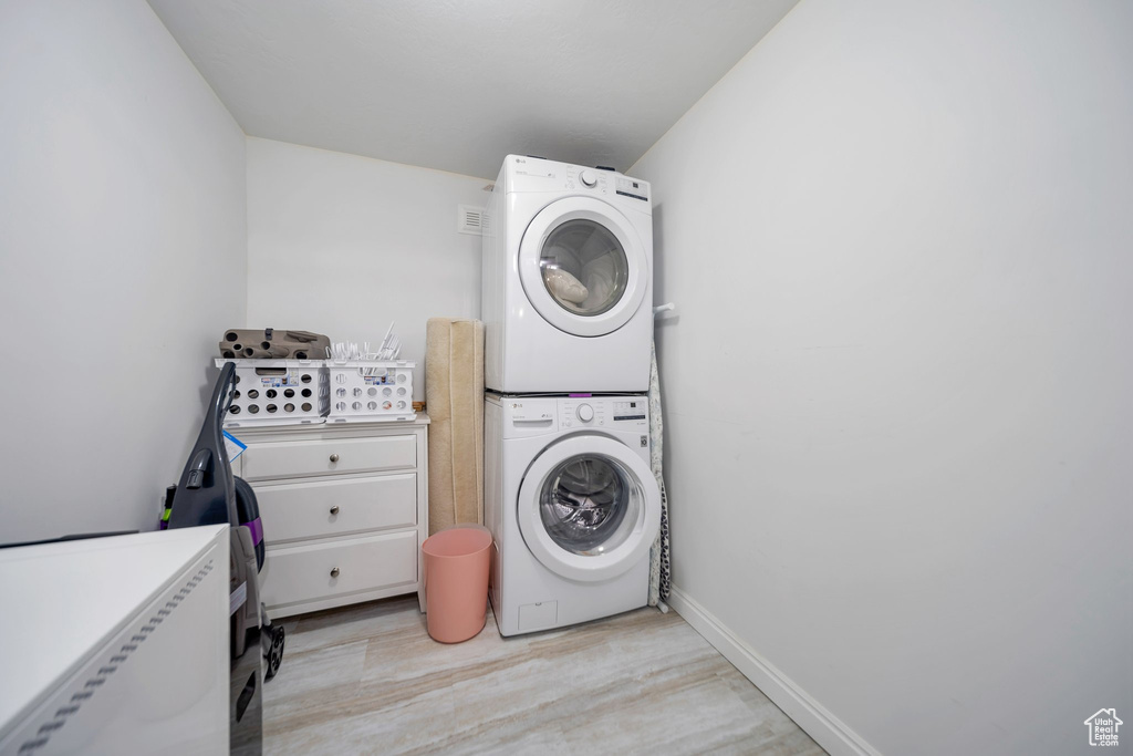 Laundry room featuring light wood-type flooring and stacked washer / dryer
