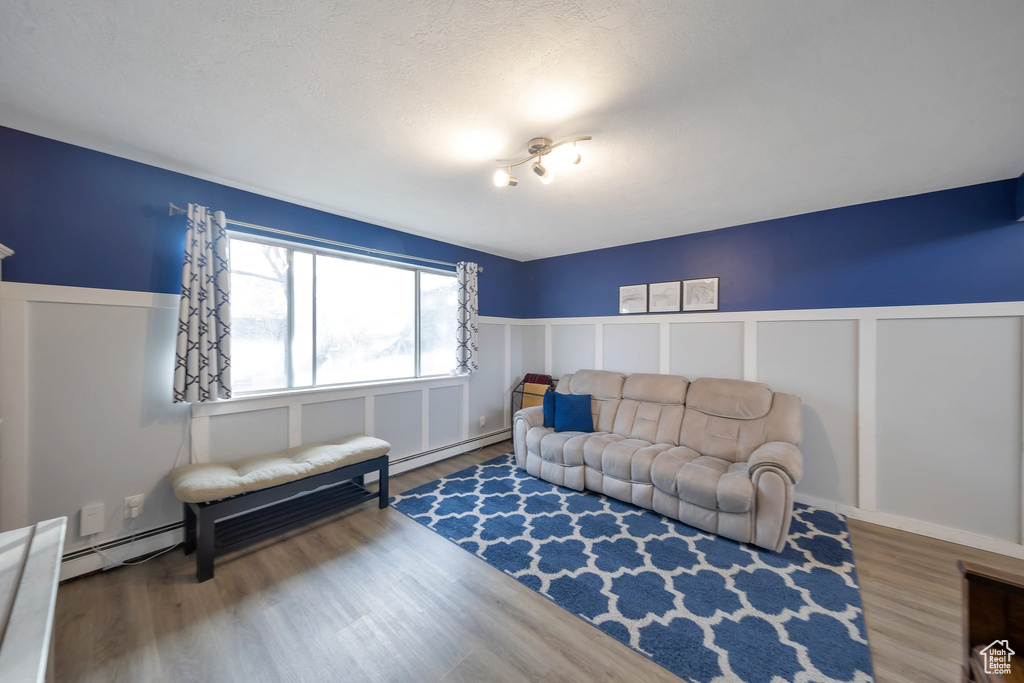 Living room with hardwood / wood-style flooring and baseboard heating