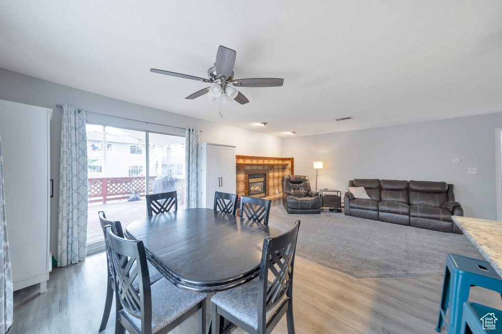 Dining area featuring a fireplace, light wood-type flooring, and ceiling fan