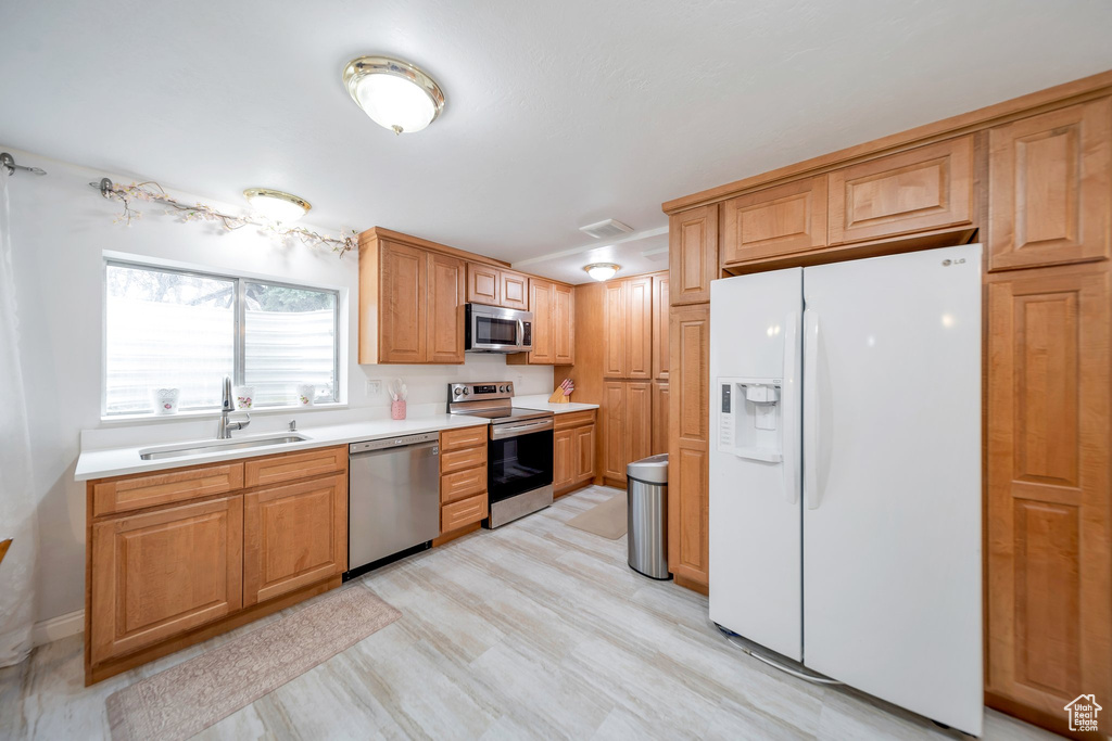 Kitchen with sink, light hardwood / wood-style flooring, and appliances with stainless steel finishes