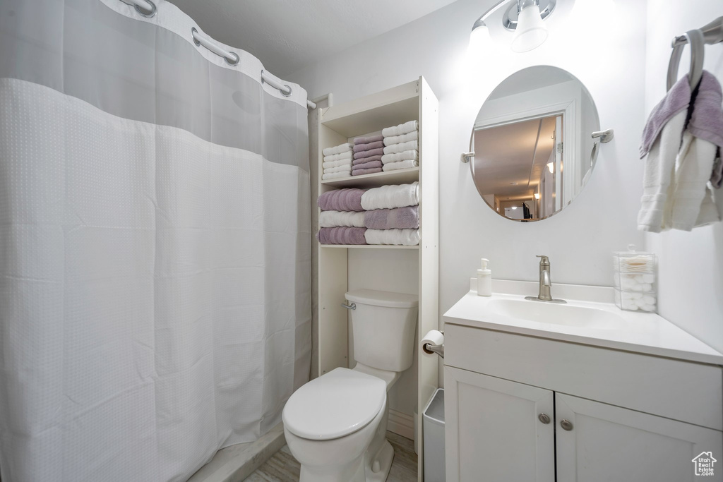 Bathroom featuring a shower with shower curtain, vanity, and toilet
