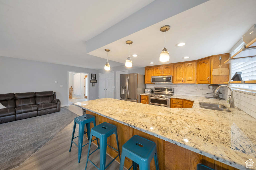 Kitchen featuring sink, a breakfast bar area, dark hardwood / wood-style floors, decorative backsplash, and stainless steel appliances