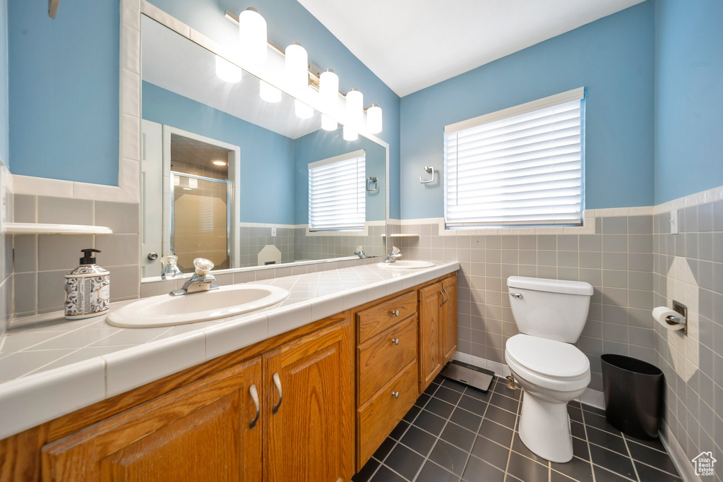 Bathroom with tile patterned floors, an enclosed shower, tile walls, and toilet