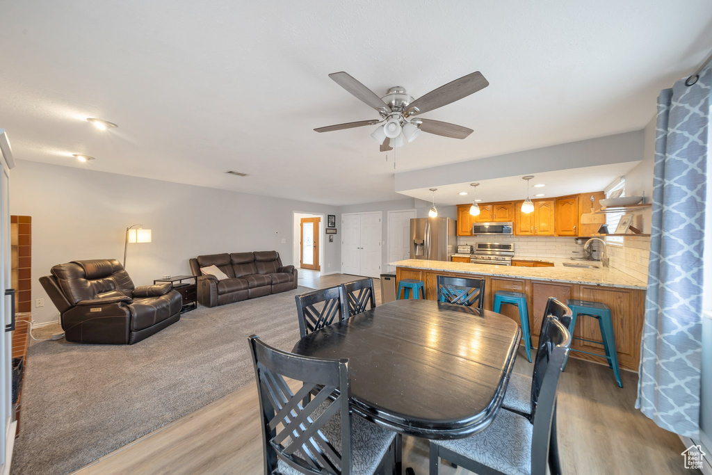 Dining space featuring ceiling fan, sink, and light hardwood / wood-style flooring