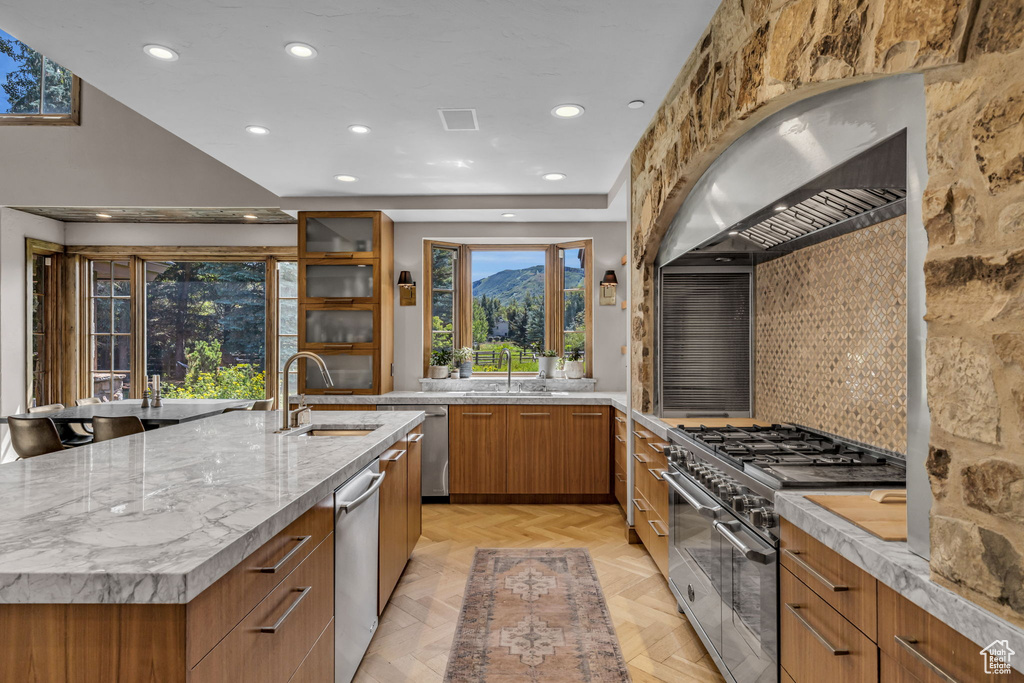 Kitchen with backsplash, a spacious island, sink, appliances with stainless steel finishes, and light parquet flooring