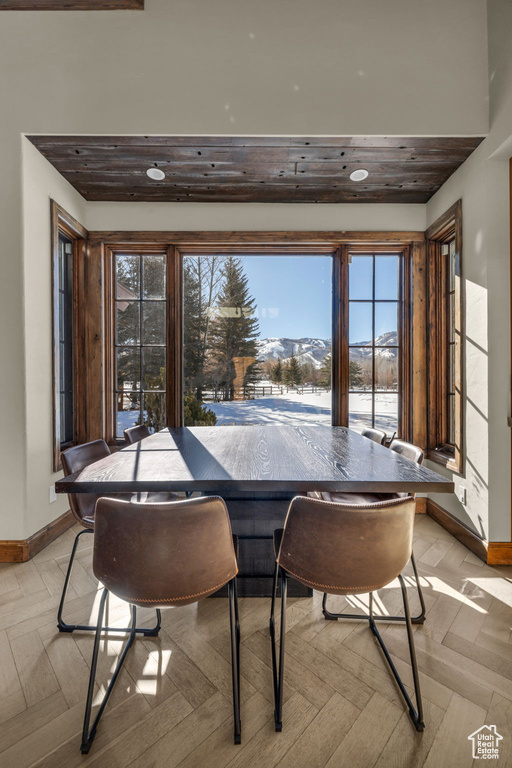 Dining area featuring a mountain view, wooden ceiling, light parquet floors, and a healthy amount of sunlight