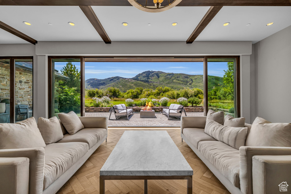Living room with a mountain view, beam ceiling, an inviting chandelier, and light parquet floors
