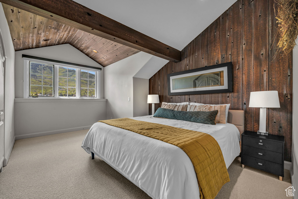 Bedroom with lofted ceiling with beams, light carpet, and wooden walls