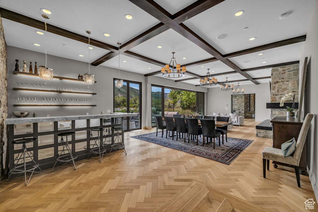 Dining room featuring beamed ceiling, a notable chandelier, bar, and light parquet flooring