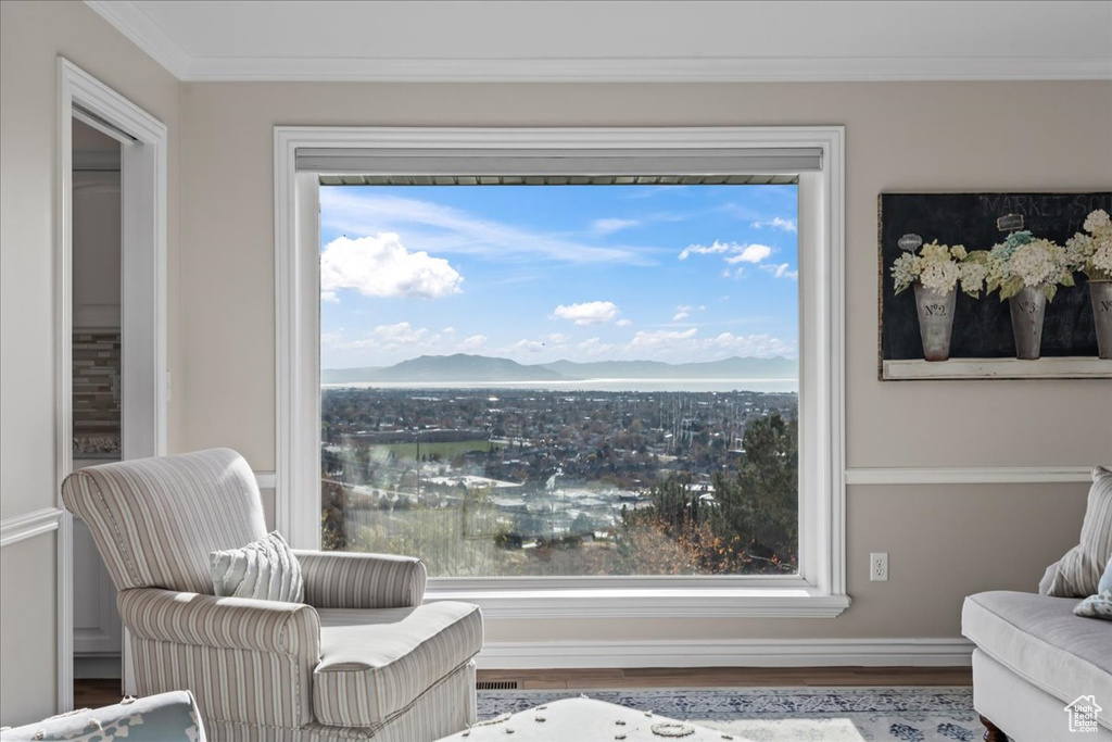 Sitting room with a mountain view, a healthy amount of sunlight, wood-type flooring, and ornamental molding