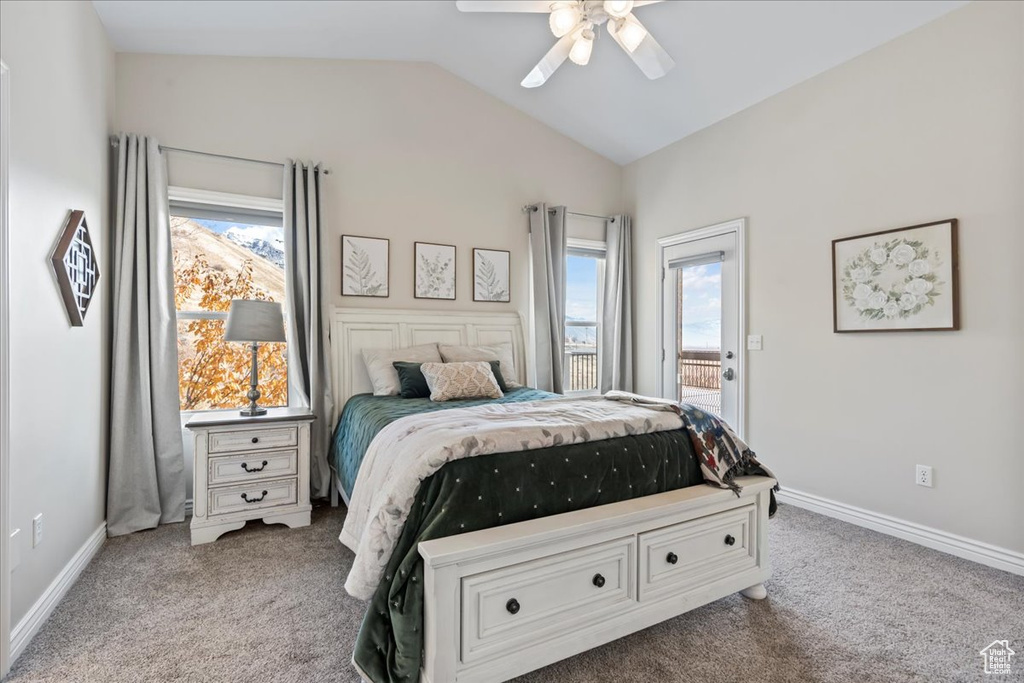 Carpeted bedroom featuring multiple windows, ceiling fan, and vaulted ceiling