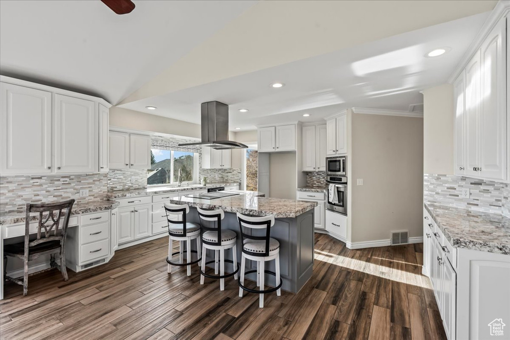 Kitchen featuring white cabinets, decorative backsplash, and island range hood