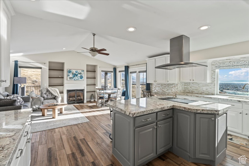 Kitchen featuring white cabinetry, dark hardwood / wood-style floors, island exhaust hood, vaulted ceiling, and black electric cooktop