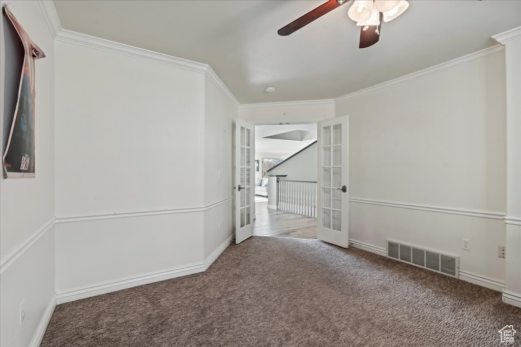 Carpeted empty room featuring ceiling fan, french doors, and ornamental molding