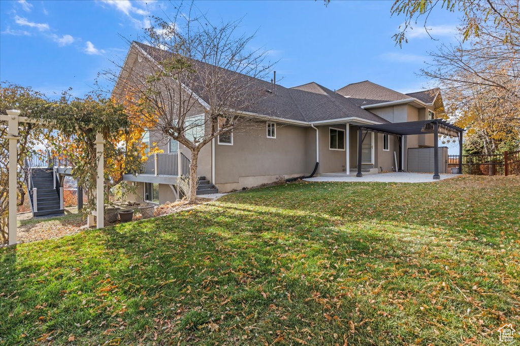 Rear view of house featuring a lawn, a pergola, and a patio