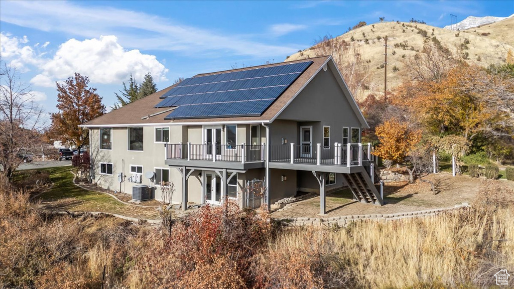 Rear view of house featuring cooling unit, a deck with mountain view, and solar panels