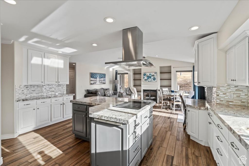 Kitchen featuring island exhaust hood, decorative backsplash, dark hardwood / wood-style flooring, and white cabinetry