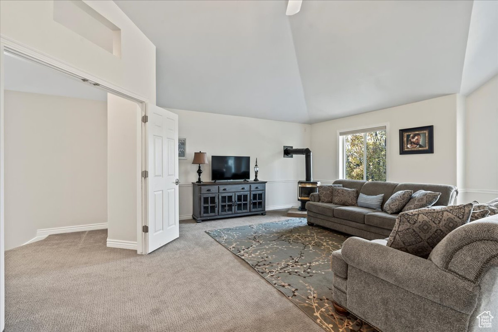 Living room with light carpet, high vaulted ceiling, and a wood stove