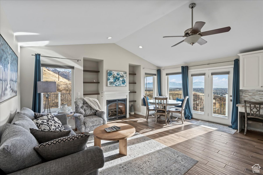 Living room featuring built in shelves, ceiling fan, vaulted ceiling, and hardwood / wood-style flooring