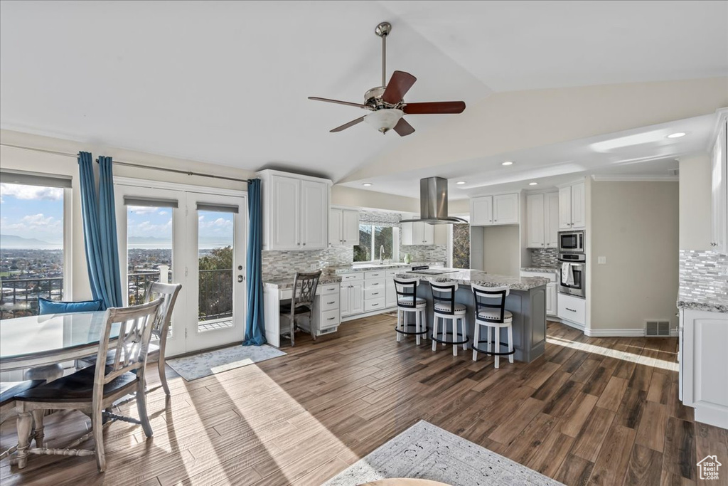 Living room featuring ceiling fan, dark hardwood / wood-style flooring, vaulted ceiling, and ornamental molding