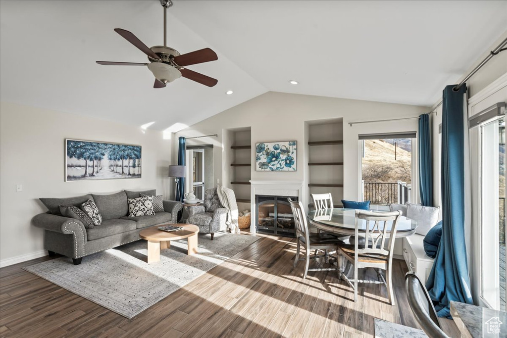 Living room featuring wood-type flooring, vaulted ceiling, and ceiling fan