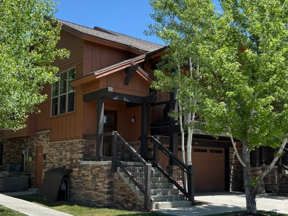 View of front of property featuring board and batten siding, an attached garage, and stairs