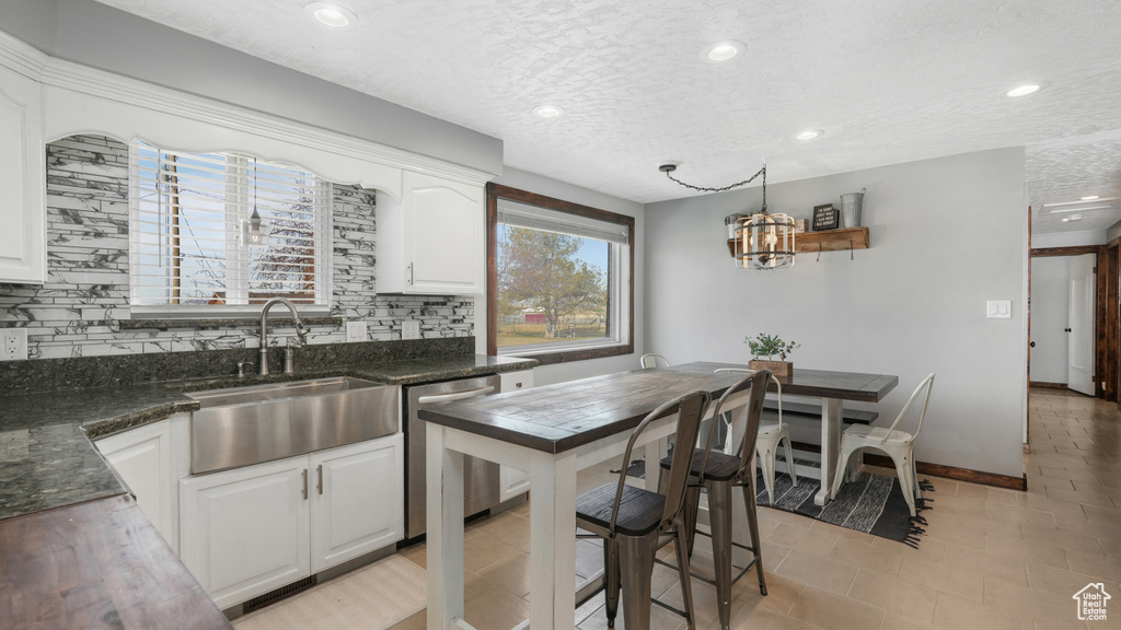 Kitchen featuring white cabinetry, decorative backsplash, sink, and stainless steel dishwasher