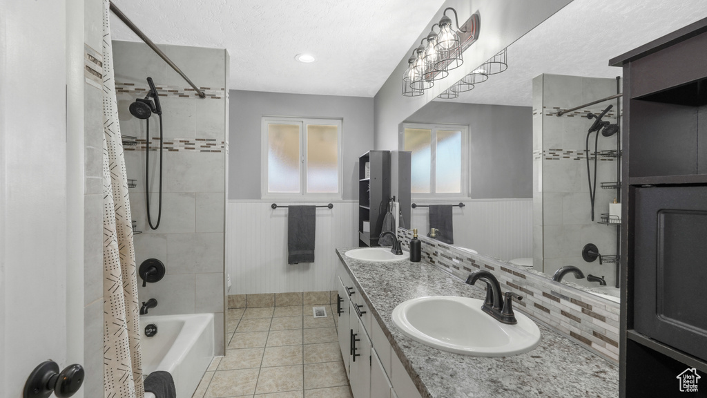 Bathroom featuring tile patterned flooring, shower / bath combination with curtain, a textured ceiling, and vanity