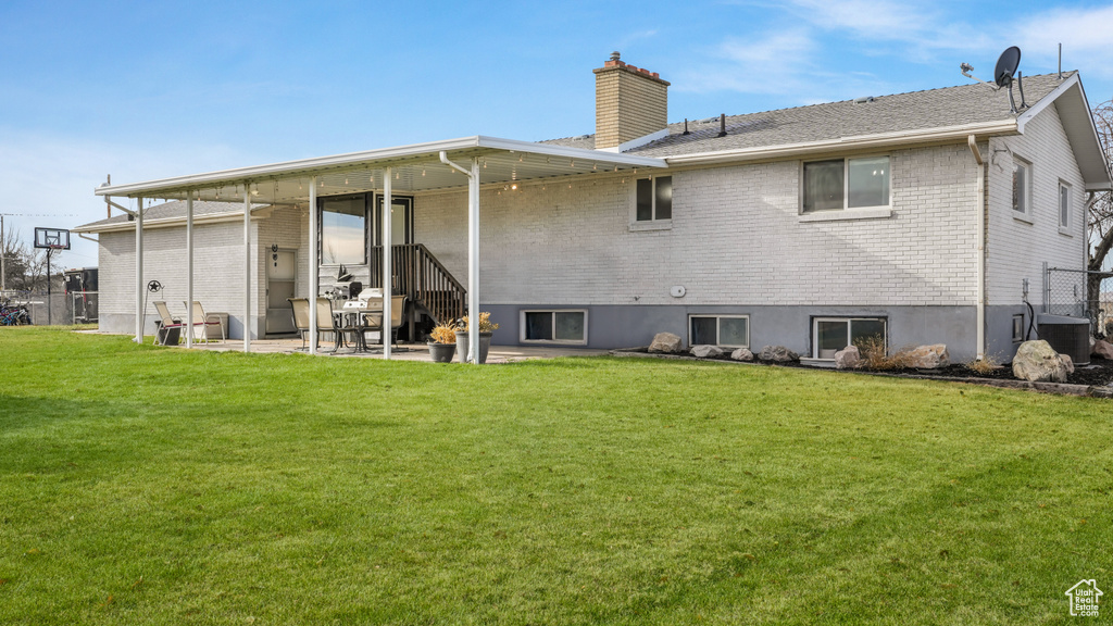 Back of house featuring a yard and central AC unit