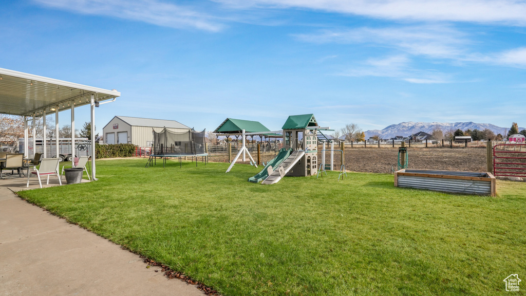 View of jungle gym with a mountain view, a trampoline, and a lawn