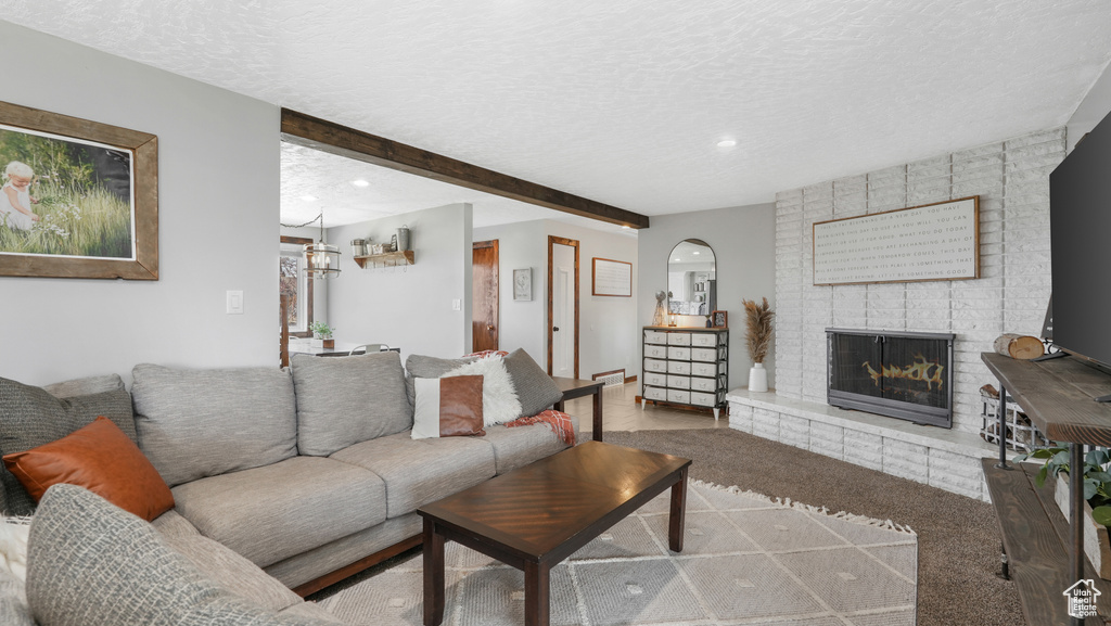 Carpeted living room featuring beamed ceiling, a textured ceiling, and a fireplace