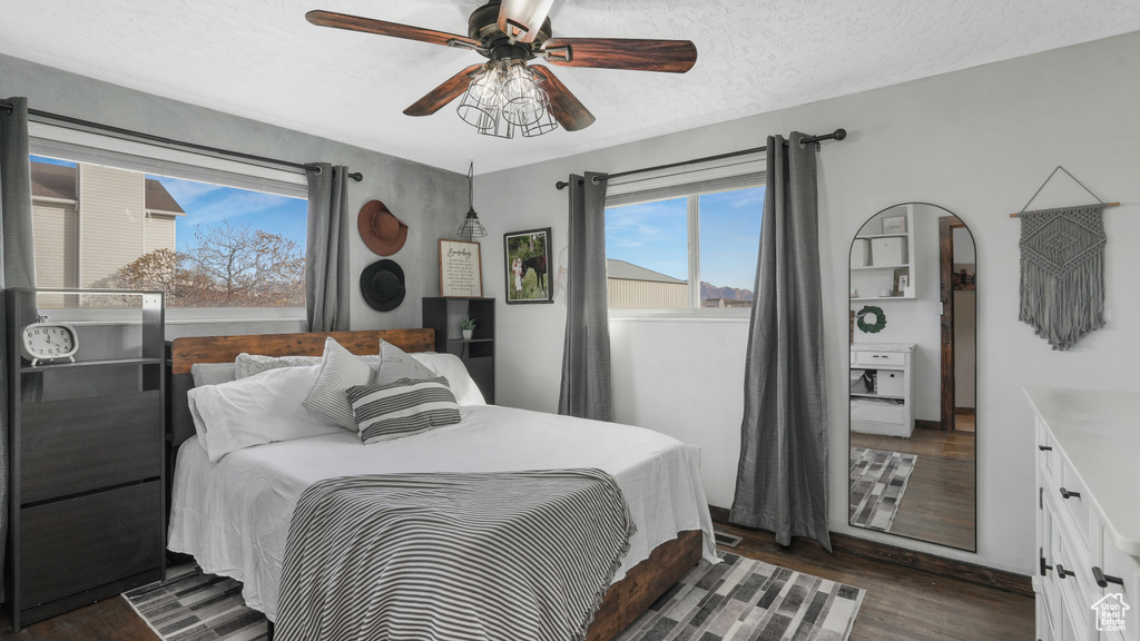 Bedroom with ceiling fan, dark hardwood / wood-style flooring, and a textured ceiling