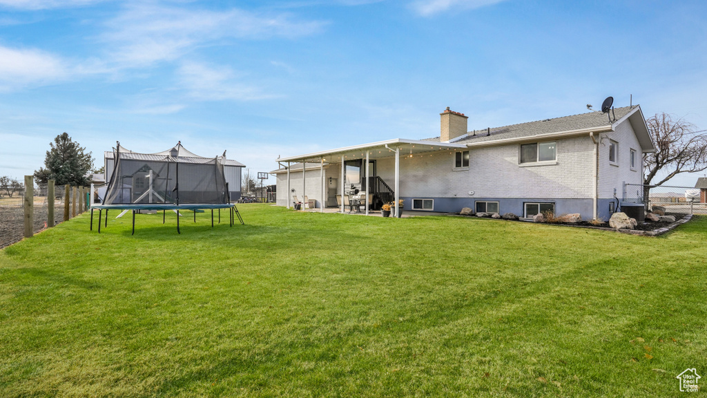 Rear view of house with a yard and a trampoline