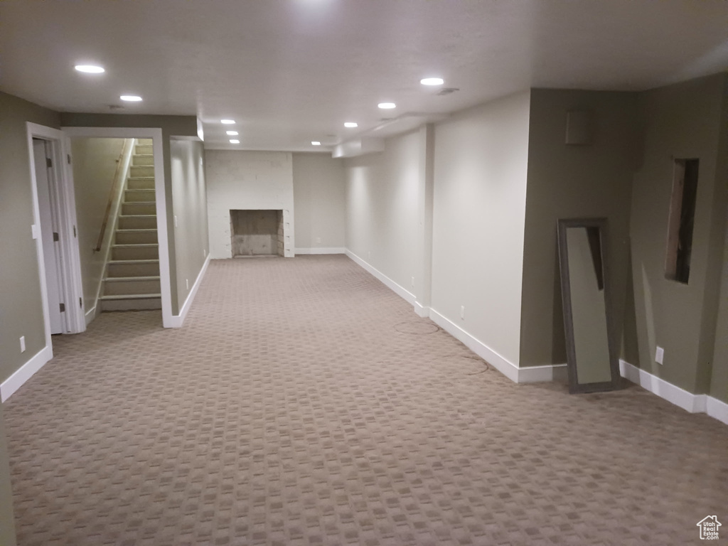Finished basement featuring recessed lighting, carpet flooring, baseboards, stairway, and a fireplace