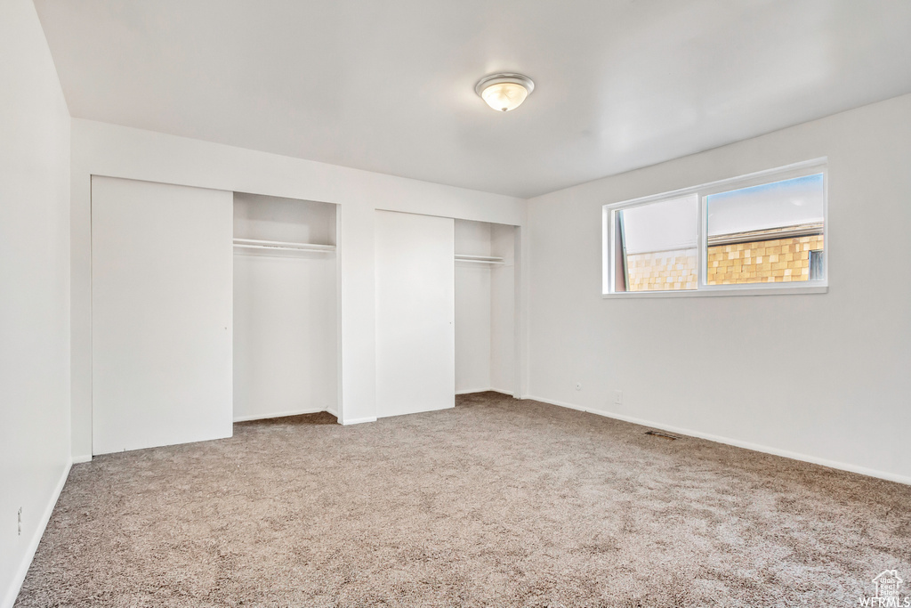 Unfurnished bedroom featuring carpet floors and multiple closets