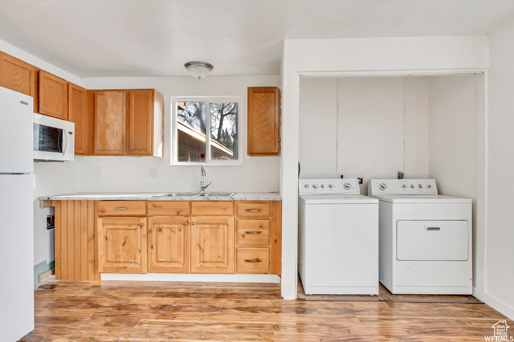 Clothes washing area with independent washer and dryer, sink, and light wood-type flooring