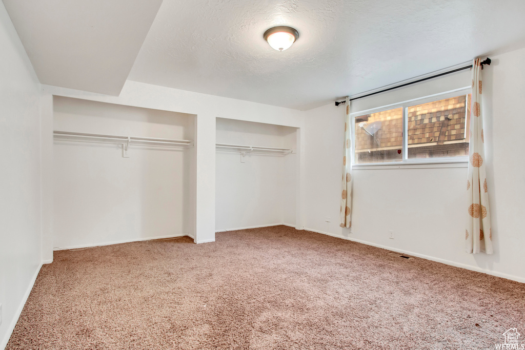 Unfurnished bedroom featuring multiple closets, carpet floors, and a textured ceiling