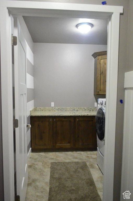 Laundry area featuring light tile patterned floors, washer / clothes dryer, and cabinets