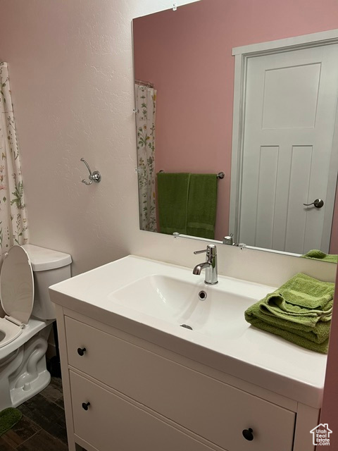 Bathroom with hardwood / wood-style floors, toilet, and vanity