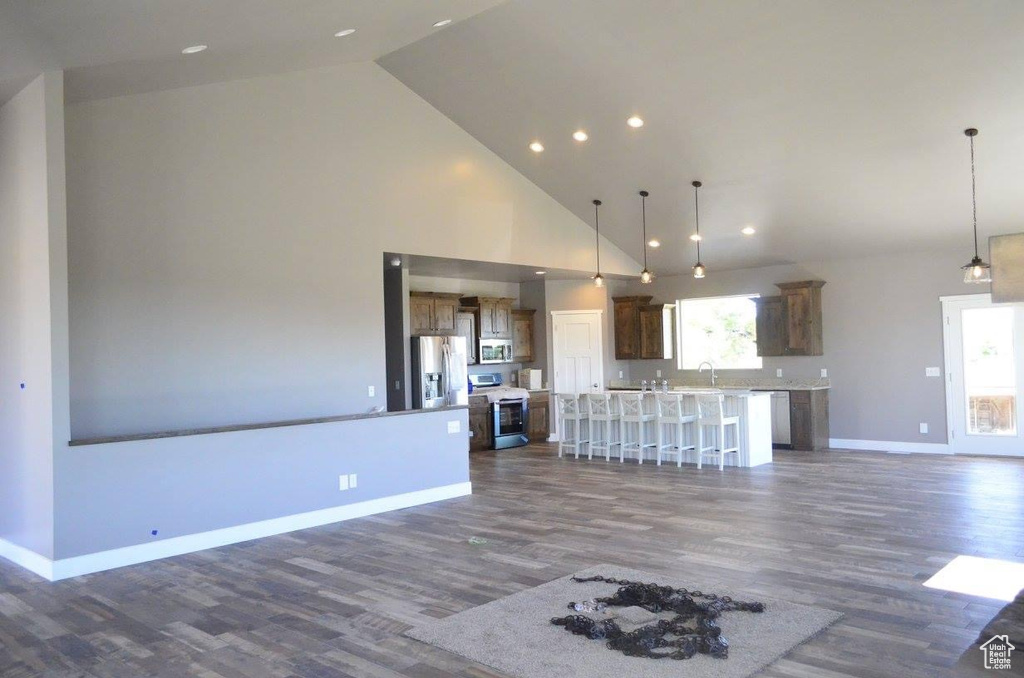 Unfurnished living room featuring sink, high vaulted ceiling, and dark wood-type flooring