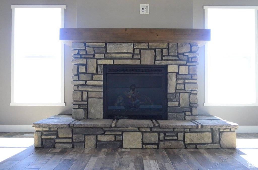 Details featuring wall chimney range hood, hardwood / wood-style floors, and a stone fireplace