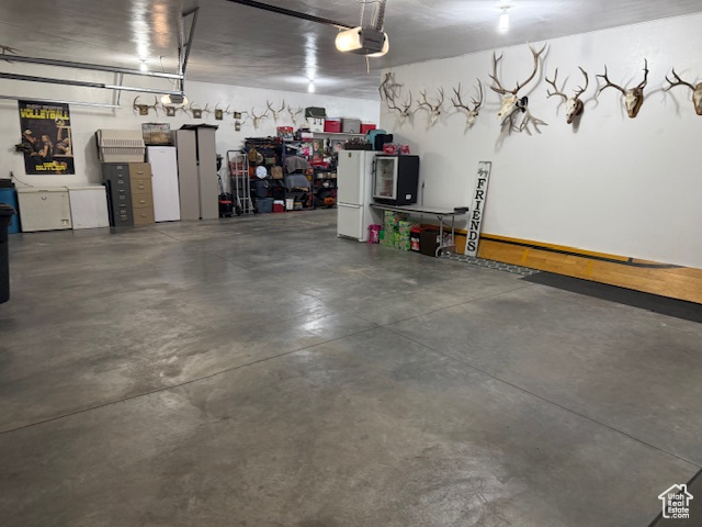 Garage with white refrigerator and a garage door opener